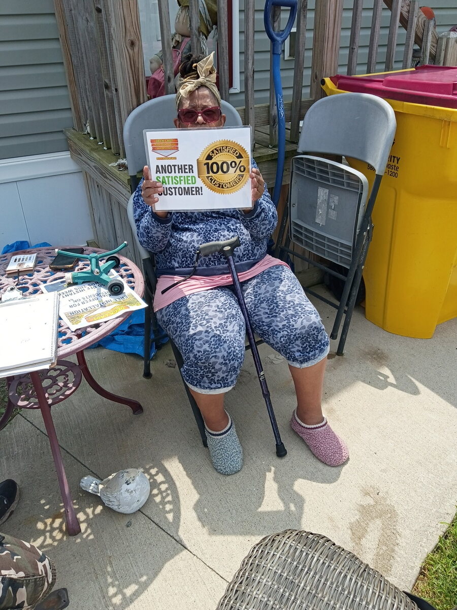 Deck Last customer seated outdoors and holding a satisfaction sign